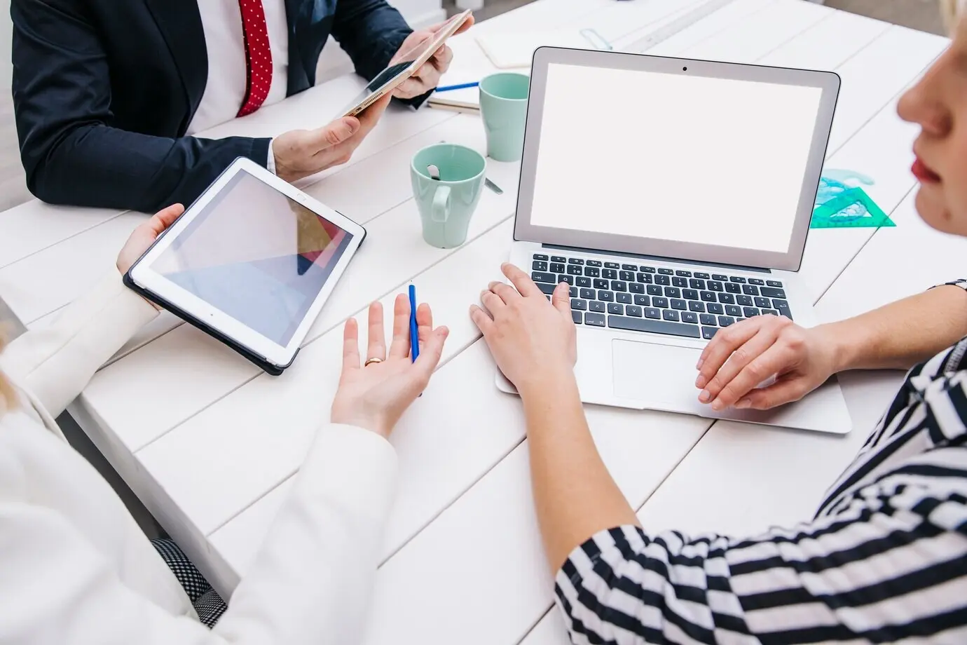 Коллеги за рабочим столом с устройствами.